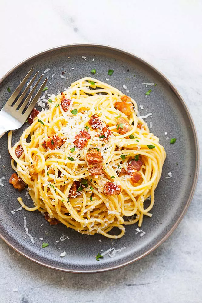 Pasta Carbonara on a plate, topped with grated cheese.